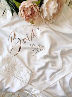 the bride's t - shirt is laying next to some flowers on top of it