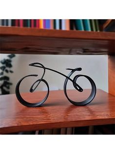 a small metal bike sitting on top of a wooden table next to a bookshelf