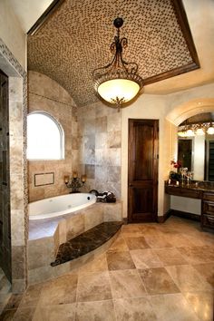 a bath room with a large tub and a chandelier hanging from the ceiling