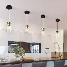 a modern kitchen with bar stools and pendant lights over the countertop, along with an island