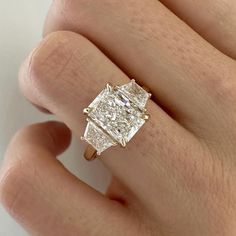 a woman's hand with a diamond ring on top of her finger, showing the center stone