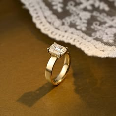 a diamond ring sitting on top of a table next to a white lace doily