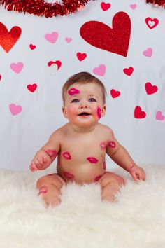 a baby is sitting on the floor with hearts painted all over it's body