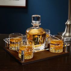 a bottle of whiskey sitting on top of a wooden tray filled with glasses and shot glasses