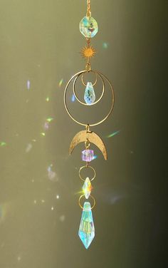 a wind chime hanging from a chain with crystals and sunbursts on it