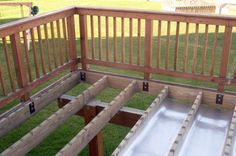 an outdoor play area with slide in the grass and wooden railings on the side