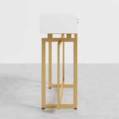 a white and gold side table with a square top on it's legs, against a plain background