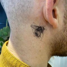 a man's neck with a small tattoo of a bee on the back of his neck