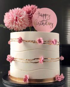 a white cake with pink flowers and a happy birthday sign on it's top