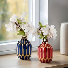 two vases with flowers in them sitting on a window sill