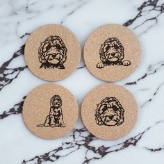 three cork coasters with dogs drawn on them sitting on a marble counter top next to each other