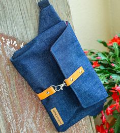 a blue bag hanging on the side of a wooden wall with flowers in the background