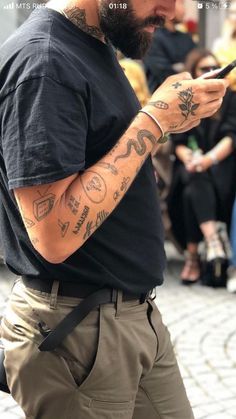 a man with tattoos is looking at his cell phone