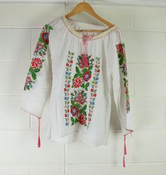 Women's Vintage Indian Blouse | Embroidered | A Condition Description Hungarian style summer blouse featuring embroidered arms and chest. Sleeves and neck fasteners. Great wardrobe staple for Summer. Made in India. Material - Cotton Brand - unbranded  Size -  see measurements   Measurements lying flat Waist - 52cm Bust - 50cm  Length - 66cm  Sleeve Length - 58cm from side neck  This is a vintage item sourced and inspected in Melbourne, Australia. Items have been washed and cared for. Please note Long Sleeve Tops With Floral Embroidery For Summer, Summer Folk Peasant Top With Embroidered Sleeves, Spring Folk Embroidered Peasant Top, Bohemian Summer Peasant Top With Embroidered Sleeves, Bohemian Peasant Top With Embroidered Sleeves For Summer, Long Sleeve Embroidered Top With Floral Design For Summer, Folk Style Long Sleeve Summer Tops, Folk Style Long Sleeve Embroidered Top For Summer, Folk Style Embroidered Long Sleeve Top For Summer