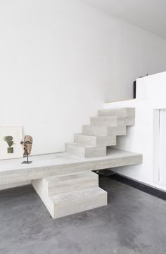 a white room with stairs and sculptures on the floor