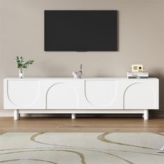 a white entertainment center with a flat screen tv mounted on it's sideboard