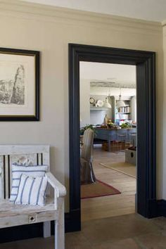 a white bench sitting in the middle of a living room next to a wall with pictures on it