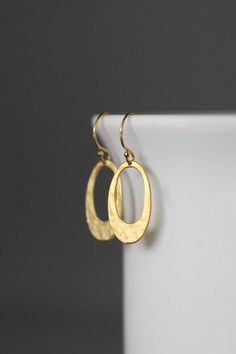 "Wonderfully lightweight 18k matte gold vermeil hammered oval cut out charms dangle from 14k gold filled balled earwires. If you are looking for the perfect pair of simple, everyday gold earrings, these are perfect! Hammered gold charms: 12x20mm Total length of earrings: almost 1 1/4\" As the owner, maker, designer, and curator of this shop, I take great pride in providing you with jewelry that you will love to wear everyday, for special occasions, and for many years to come. Please read my Shop Oval Yellow Gold Brass Earrings, Elegant Oval Hammered Earrings, Nickel Free Gold Oval Earrings, Oval Gold Brass Earrings, Nickel-free Gold Oval Earrings, Gold Plated Oval Hammered Jewelry, Hammered Yellow Gold Oval Earrings, Oval Gold Plated Hammered Jewelry, Yellow Gold Oval Hammered Earrings