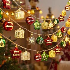 christmas ornaments are hanging on a string in front of a decorated christmas tree with lights