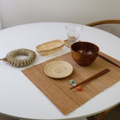 a white table topped with a bowl and chopsticks next to a wooden bowl