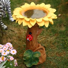 a statue of a sunflower with a ladybug on it next to flowers