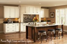 a large kitchen with white cabinets and black counter tops, along with stools in front of the island