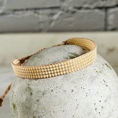 a close up of a stone with a bracelet on it's side and a brick wall in the background