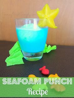 a glass filled with blue liquid sitting on top of a table next to toy animals