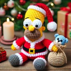 a crocheted christmas ornament sitting next to a teddy bear and gift box