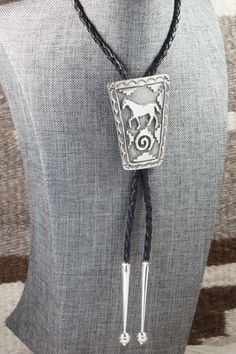 This sterling silver bolo tie featuring a horse was made by Navajo silversmith Emerson Kinsel. The back is signed K and stamped sterling.Tie Length: 23"Length: 2 1/2"Width: 2"TipsLength: 2 1/4"Width: 3/8"Free shipping on all orders! We ship with USPS and always include tracking. All orders ship within a day of payment.Returns are accepted up to 30 days after you receive your order. Just send us a message. Our shop offers cash back or store credit. The item must be returned in new condition. Artisan Silver Lariat Necklace In Sterling Silver, Southwestern Lariat Bolo Tie For Rodeo, Silver Engraved Lariat Jewelry, Engraved Silver Lariat Jewelry, Artisan Hand-tooled Jewelry For Rodeo, Concho Lariat Bolo Tie For Western-themed Events, Vintage Lariat Bolo Tie For Ranch, Vintage Lariat Bolo Ties For Ranch, Western Lariat Bolo Ties For Rodeo