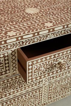 an intricately designed wooden box with drawers and handles on the bottom, is shown