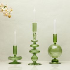 three green glass candlesticks sitting next to each other on a white counter top