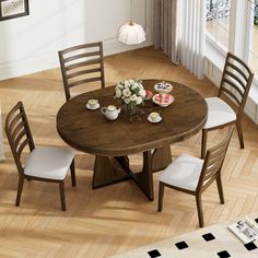 a dining room table with four chairs around it and plates on the table, in front of a window