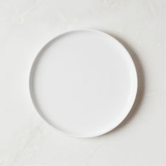 an empty white plate sitting on top of a table