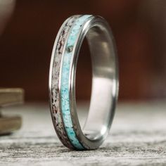 a wedding band with turquoise and silver inlays on top of two stacked books