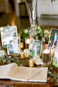 a table topped with pictures and candles on top of a wooden table covered in greenery