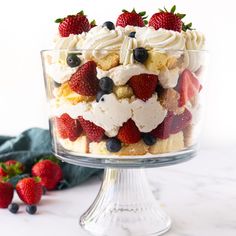 a trifle with strawberries, blueberries and other fruit on top in a glass dish