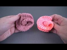 two small crocheted objects are being held in their hands, one is pink and the other is orange