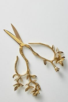 a pair of gold scissors with leaves on them