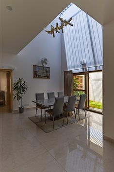 the dining room table is surrounded by gray chairs and an open skylight above it