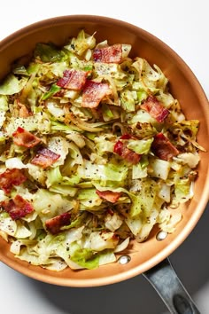 a brown bowl filled with lots of food on top of a white table next to utensils