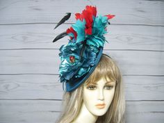 "I absolutely love this color combination! It just works. Red and turquoise with a touch of black. Yummy! One of a kind! I only have one! The base is a 9\" dark turquoise blue teardrop shape with matching loops, red and turquoise feather twist, black wispy feathers sprinkled throughout and a large metallic turquoise blue flower with a red center. I know you can't tell by the picture, but this is a large fascinator and is so much better in person! Check out all my other hats and fascinator in my Handmade Red Party Hat, Turquoise Fitted Hat For Party, Turquoise Fitted Party Hat, Fitted Turquoise Hat For Party, Spring Party Mini Hat In Turquoise, Whimsical Blue Fascinator For Party, Handmade Blue Party Hat, Blue Whimsical Mini Hats For Party, Whimsical Blue Mini Hats For Party