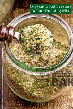 a glass jar filled with food on top of a wooden table next to a spoon