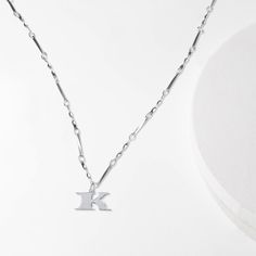 We've transformed the font used on U.S. currency into letter necklaces, so that you can channel in your own personal fortune. The letter K charm is embellished with subtle black enamel detailing along the side and our signature wave design on the back. The twisted bar chain is adjustable so you can wear it as a choker or everyday pendant. These initial necklaces are intended as a form of self expression for you or the Ks in your life. Charm Dimensions: ~12mm / 0.5" (h) Chain Length: 16"-20" adju Dainty Silver Initial Pendant Chain Necklace, Dainty Silver Chain Necklace With Initial Pendant, Silver Necklace With Initial Pendant And Paperclip Chain, Dainty Silver Initial Necklace With Adjustable Chain, Trendy Silver Initial Pendant Necklace, Trendy Initial Pendant Necklace, Silver Initial Necklace With Adjustable Clavicle Chain, Trendy Silver Initial Necklace With Clavicle Chain, Adjustable Silver Initial Necklace With Clavicle Chain