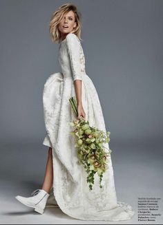 a woman in a white dress holding a bouquet and wearing high heeled shoes is posing for the camera