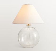 a clear glass lamp with a white shade