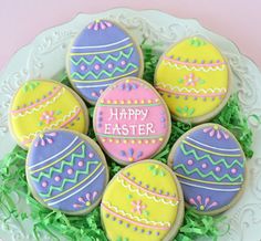 decorated cookies on a plate with the words happy easter written on them in bright colors