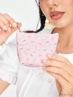 a woman is holding a pink purse with white birds on it