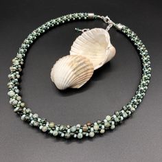 "This is an earthy, neutral necklace that will work with so many of your outfits. Warm forest green and contrasting seafoam green blend together with some beautiful semi-precious stones. The center segment features 4mm round African turquoise beads. Considered a stone of transformation and evolution, African turquoise (actually a form of jasper) is believed to awaken those who carry it to their highest spiritual purpose. The necklace measures 17 1/2\" long, and includes a 2 1/2\" extender, for a maximum length of 19\". Bali style sterling silver end caps give the finishing touch to this beautiful piece. The necklace is created using an ancient Japanese braiding technique called Kumihimo. A wooden stand called a marudai is used as a loom. Multiple cords are beaded with carefully selected co Adjustable Green Crystal Necklace, Green Beaded Multi-strand Turquoise Necklace, Green Multi-strand Hand-strung Beaded Necklaces, Green Multi-strand Hand-strung Necklaces, Artisan Green Necklace With Tiny Beads, Adjustable Single Strand Green Crystal Necklace, Adjustable Turquoise Necklace With Faceted Green Beads, Adjustable Green Turquoise Necklace With Round Beads, Adjustable Green Hand-strung Beaded Necklaces