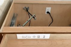 an electrical outlet in a wooden cabinet with two wires plugged into the outlets